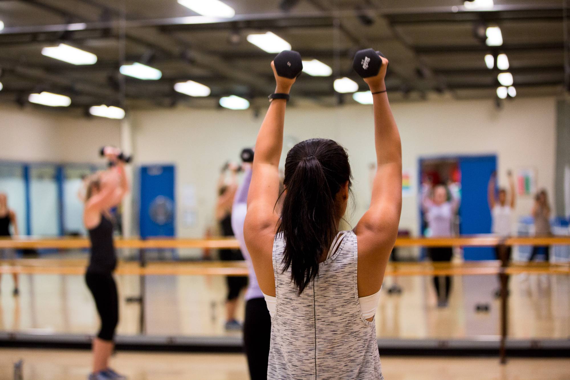 A Group Exercise participant lifting weights.